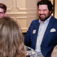 A group of alumni smile and laugh at a table